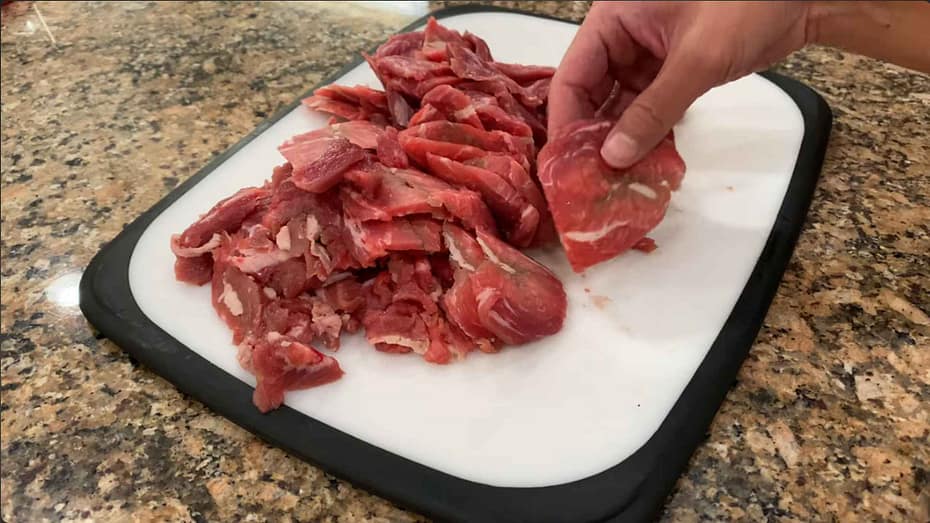 Beef cut in thin slices on a cutting board while partially frozen