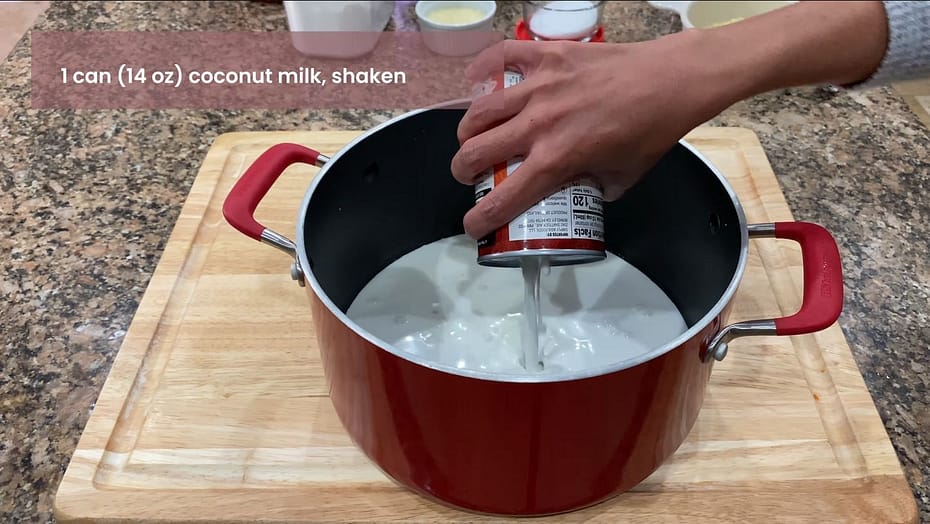 Adding a can of coconut milk to the pot