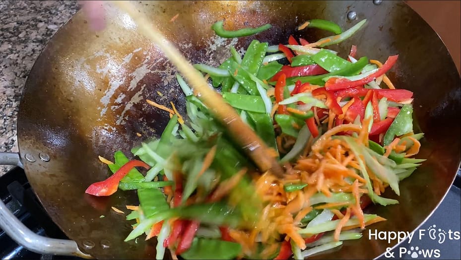 Mixing vegetables in a wok with a wooden spoon