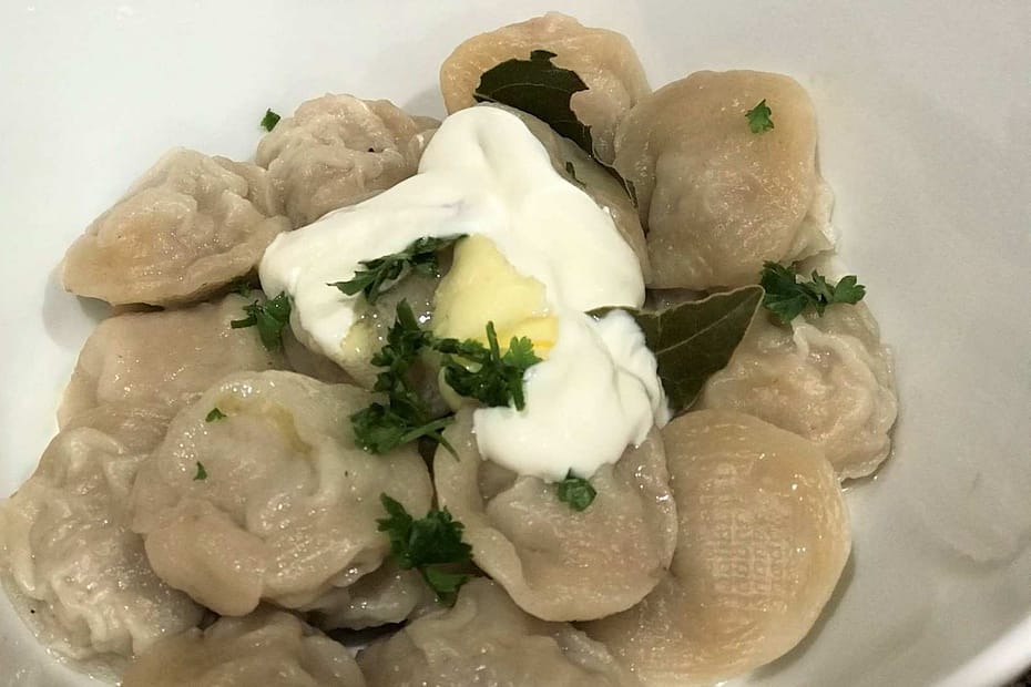Homemade cooked pelmeni with sour cream in a bowl