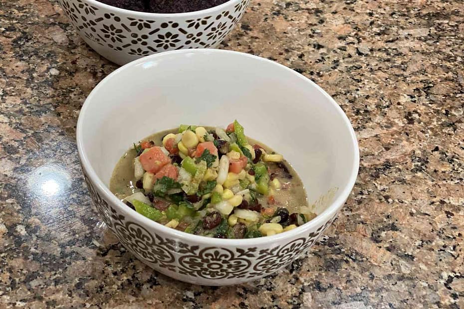 black bean salsa with corn, cilantro, onion, tomato, jalapeno, lime juice, and vinagrete in a bowl.