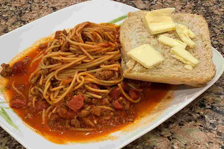 sweet filipino spaghetti with french bread, hotdog, and sausage.