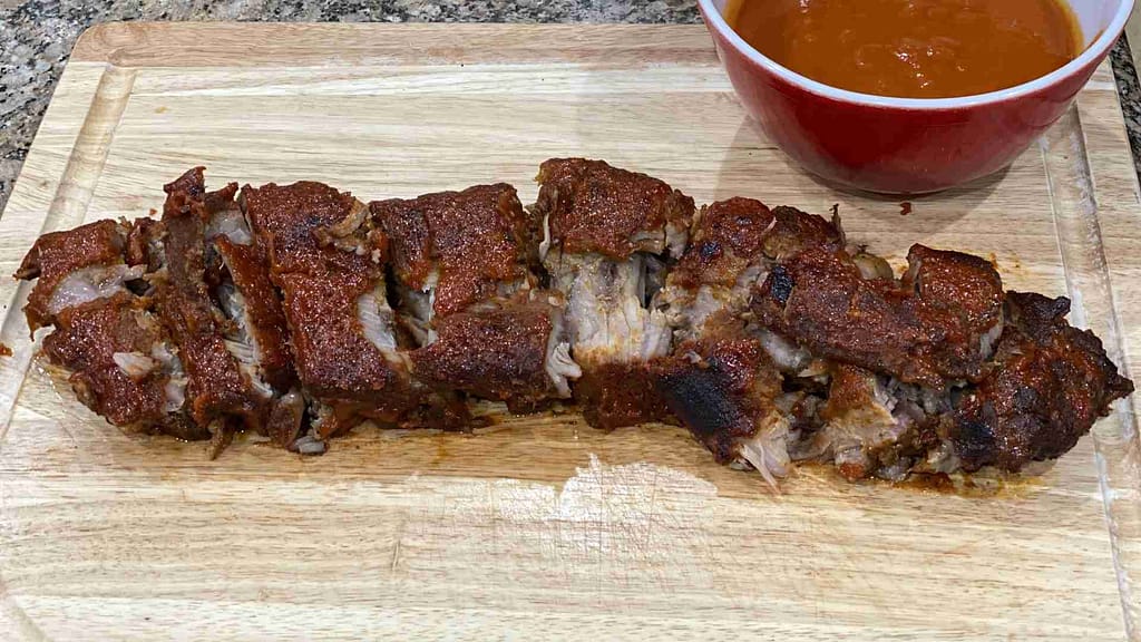 Hawaiian Baby Back Ribs on a cutting board with a bowl of coconut guava sauce