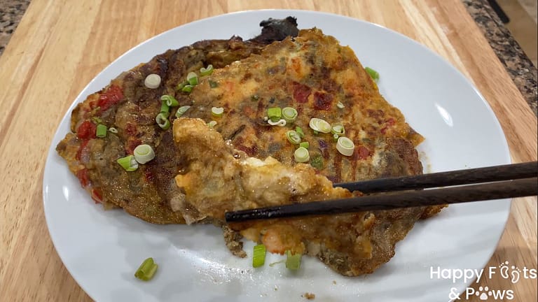 Two filipino style grilled eggplant omelets on a plate with onions and chopsticks