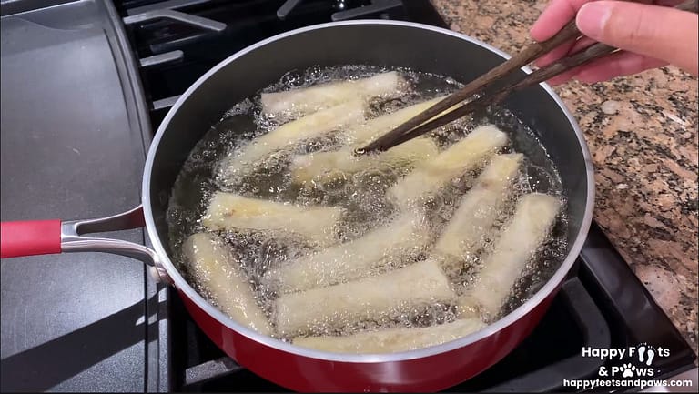 Banana Rum Rolls frying in oil on a stove in a pot