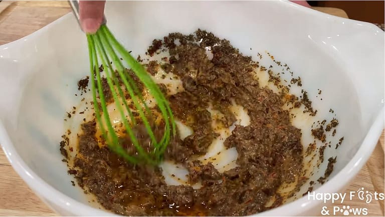 wisking sun dried tomato vinaigrette in a glass bowl