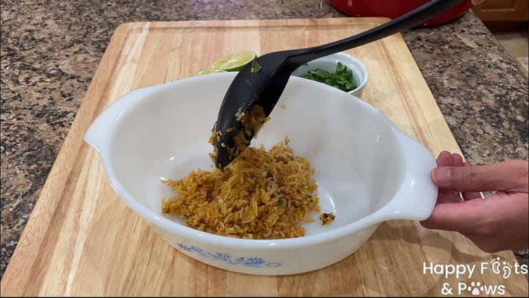 a scoop of spanish rice being added to a glass bowl