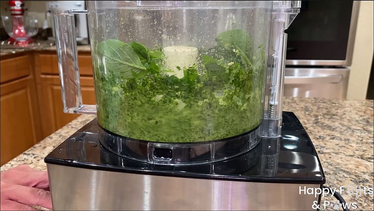 Fresh basil pesto being ground up in a food processor for basil pesto