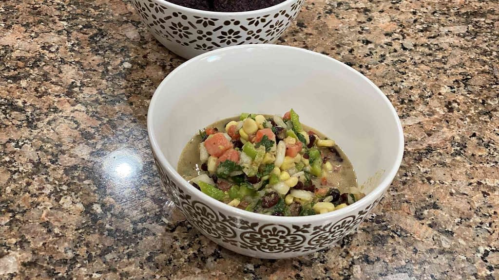 black bean salsa with corn, cilantro, onion, tomato, jalapeno, lime juice, and vinagrete in a bowl.