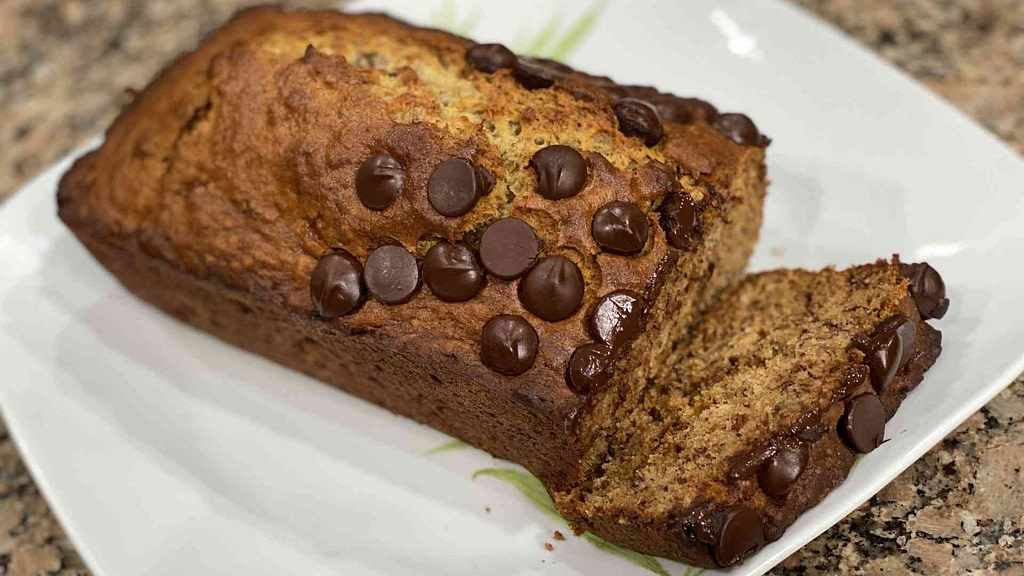 fresh baked banana bread on a plate with chocolate chips on top