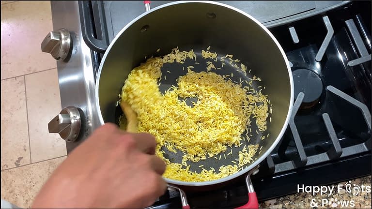 woman's hand stirring rice in pot on stove for Spanish rice recipe