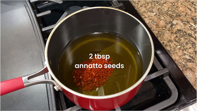 A pot with annatto oil seeds being cooked for annatto oil recipe