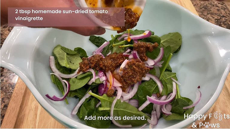 adding home made sun-dried tomato vinaigrette to spinach salad