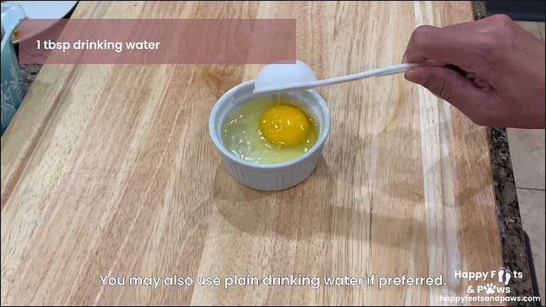 raw egg with water being added in glass container for Banana Rum Rolls recipe